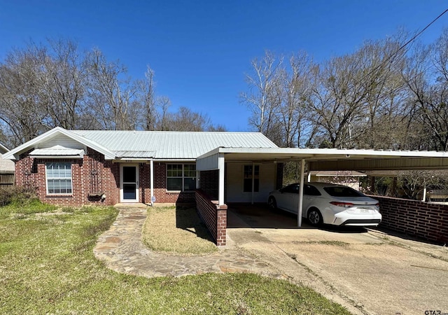 view of front facade featuring a carport, brick siding, driveway, and metal roof