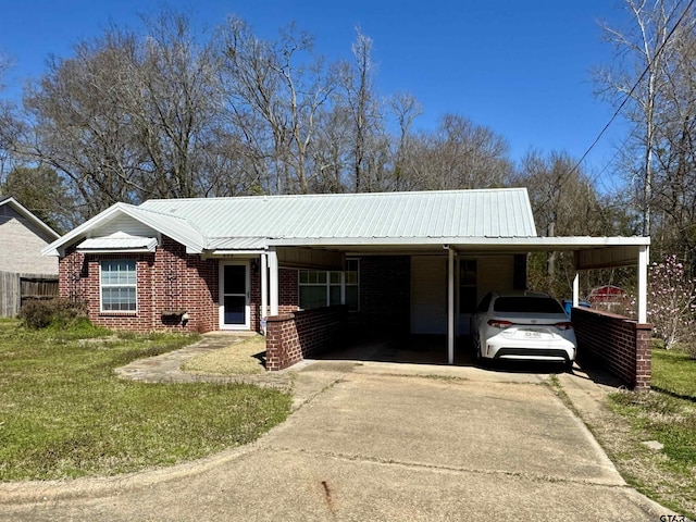 ranch-style house with an attached carport, concrete driveway, brick siding, and metal roof