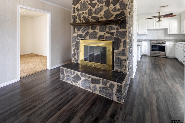 unfurnished living room with a ceiling fan, visible vents, a fireplace, dark wood-style flooring, and ornamental molding