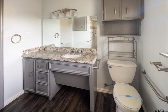 bathroom with vanity, toilet, wood finished floors, and baseboards