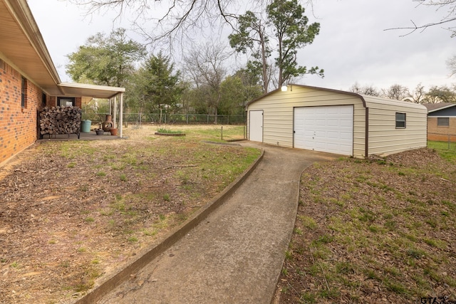 view of yard featuring an outbuilding, fence, driveway, and a detached garage