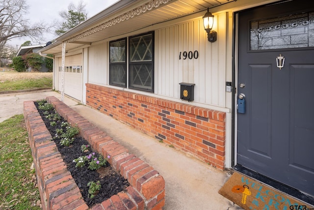 doorway to property with brick siding, crawl space, board and batten siding, and an attached garage