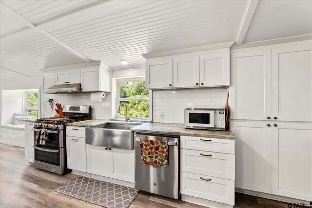 7928 Fm 127, Mount Pleasant, TX 75455 - kitchen with stainless steel appliances, a sink, decorative backsplash, white cabinets, and under cabinet range hood
