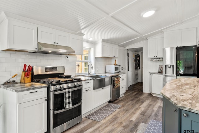 7928 Fm 127, Mount Pleasant, TX 75455 - kitchen featuring appliances with stainless steel finishes, under cabinet range hood, a sink, white cabinetry, and vaulted ceiling