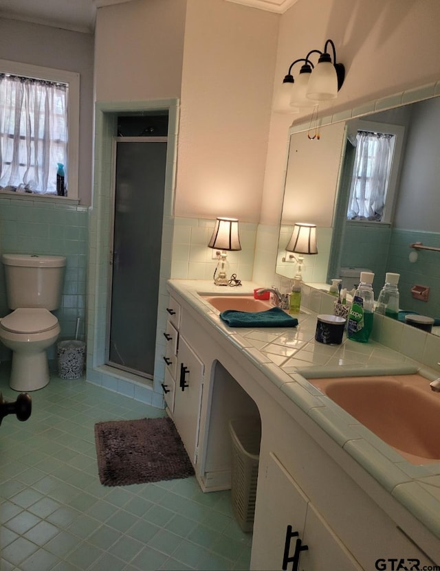 bathroom with tile walls, vanity, an enclosed shower, and tile patterned flooring