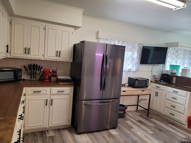 kitchen featuring stainless steel fridge, ornamental molding, white cabinetry, and wood-type flooring