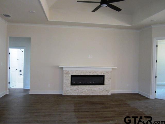 unfurnished living room featuring a stone fireplace, dark hardwood / wood-style flooring, ornamental molding, and ceiling fan