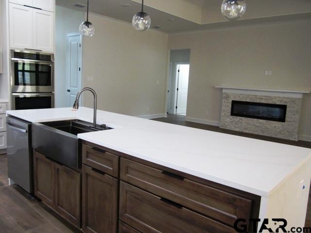 8016 Crooked Trl, Tyler, TX 75703 - kitchen featuring open floor plan, appliances with stainless steel finishes, light countertops, a fireplace, and decorative light fixtures