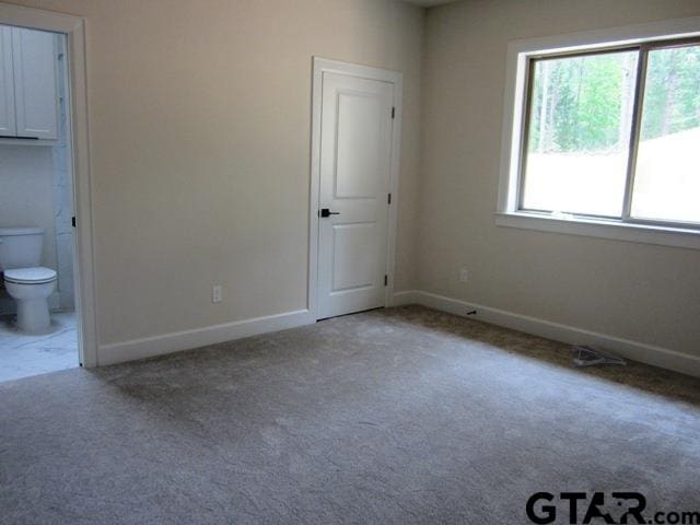 unfurnished bedroom featuring carpet floors and connected bathroom