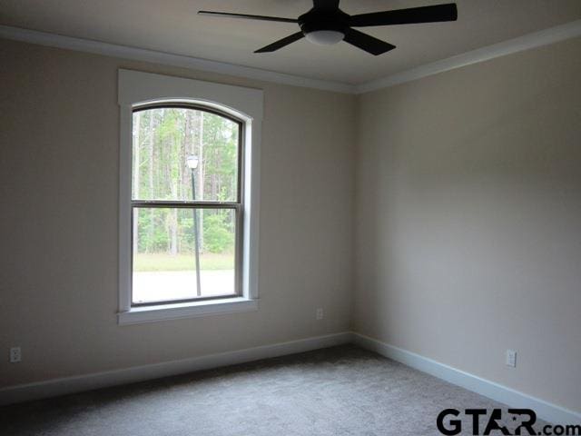 carpeted empty room featuring ornamental molding, a wealth of natural light, and ceiling fan