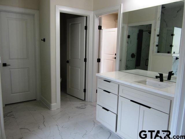 bathroom featuring a shower with door and vanity