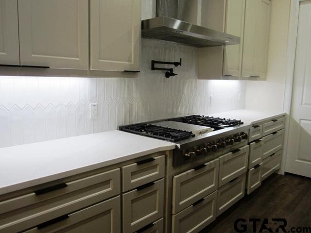 kitchen featuring dark hardwood / wood-style flooring, wall chimney range hood, gray cabinets, and stainless steel gas stovetop