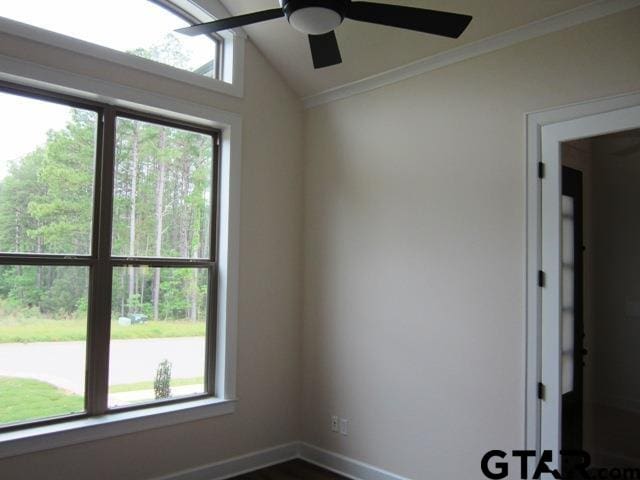 empty room featuring a wealth of natural light, ceiling fan, crown molding, and vaulted ceiling