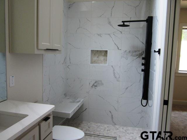 bathroom featuring vanity, toilet, and tiled shower