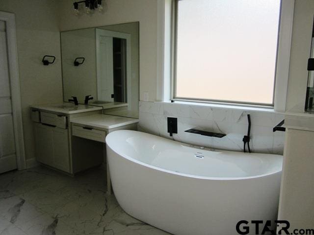 bathroom featuring vanity, a healthy amount of sunlight, and a bathtub