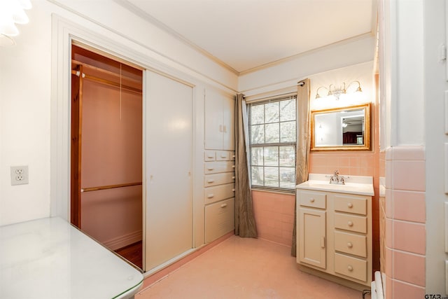 bathroom with crown molding, vanity, and tile walls