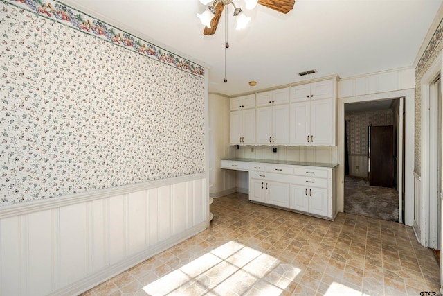 kitchen with white cabinetry, ceiling fan, and crown molding