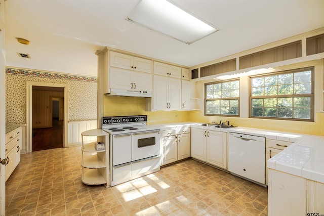 kitchen featuring tile countertops, sink, white appliances, and kitchen peninsula