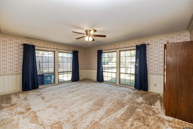 carpeted spare room featuring ceiling fan and crown molding