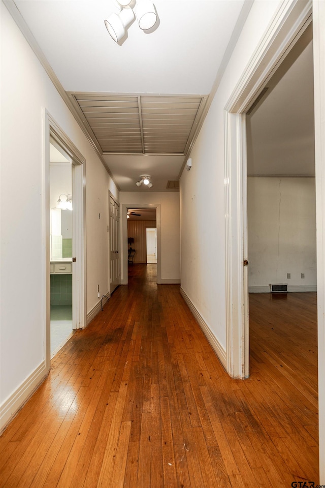 hallway with wood-type flooring and crown molding