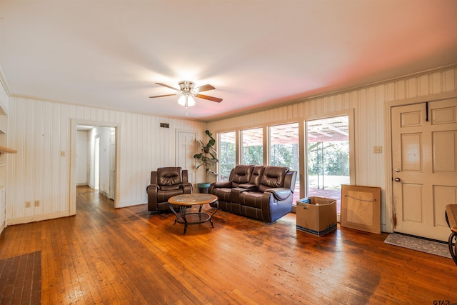 living room with ceiling fan, dark wood-type flooring, and ornamental molding