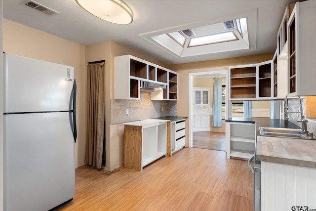 kitchen featuring open shelves, visible vents, decorative backsplash, light wood-style floors, and freestanding refrigerator