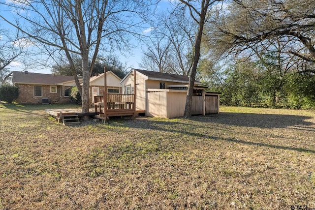 exterior space featuring brick siding, a lawn, and a wooden deck