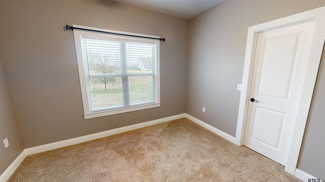carpeted empty room featuring baseboards