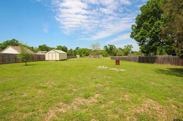 view of yard featuring a shed, a fenced backyard, and an outbuilding