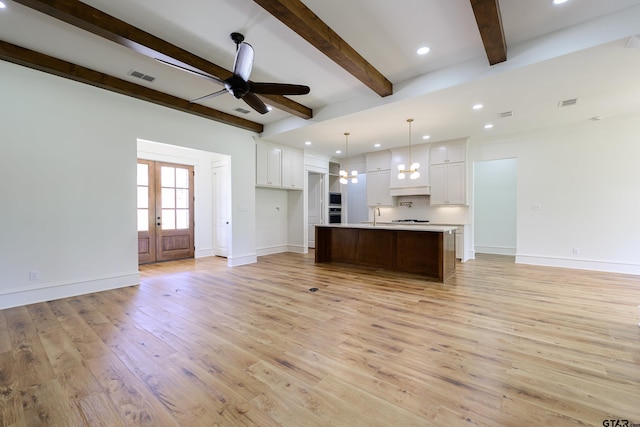 kitchen with visible vents, a center island with sink, white cabinetry, and light countertops