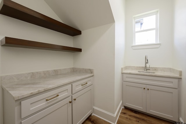 bar featuring vaulted ceiling, dark wood-style flooring, a sink, and baseboards