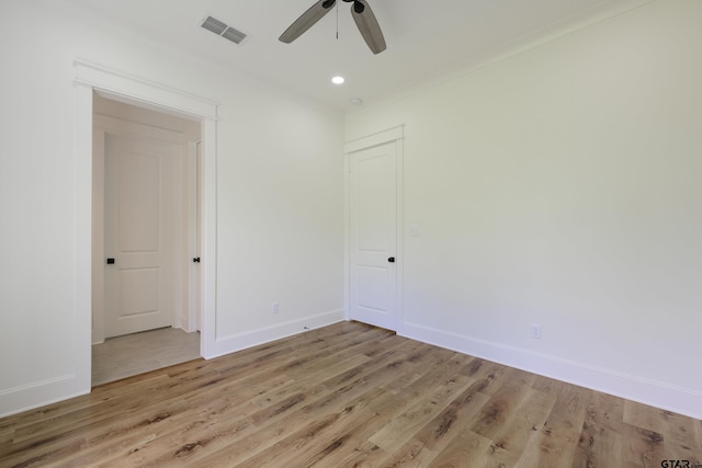 spare room featuring crown molding, visible vents, ceiling fan, wood finished floors, and baseboards