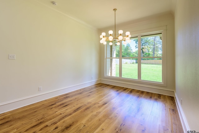 unfurnished room with baseboards, crown molding, wood finished floors, and a notable chandelier