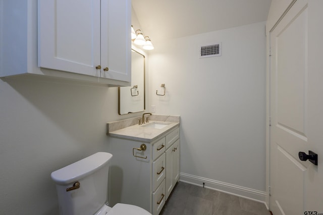 bathroom with visible vents, toilet, vanity, wood finished floors, and baseboards