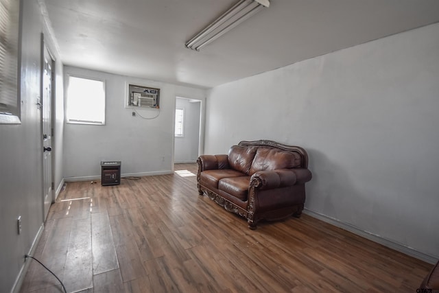 sitting room with a wall mounted air conditioner, baseboards, and wood finished floors