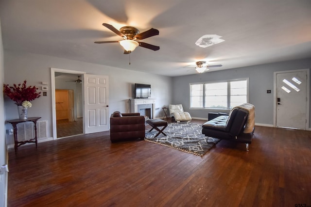 living room featuring dark wood-style floors, a fireplace, baseboards, and a ceiling fan