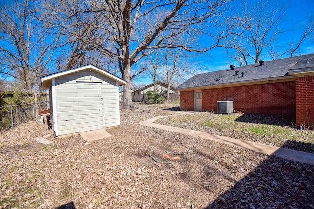 view of yard featuring central air condition unit, a storage shed, fence, and an outbuilding