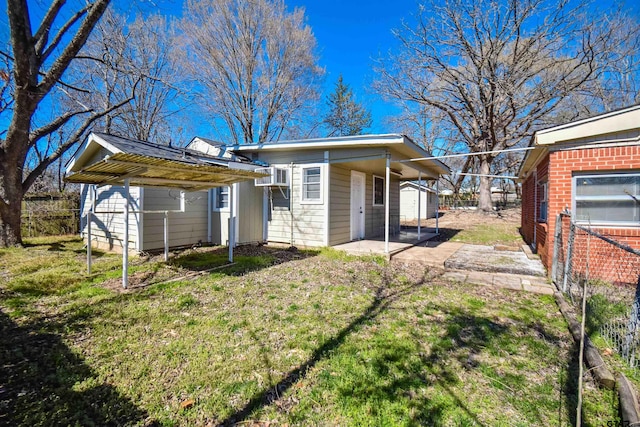 back of house with a storage shed, a lawn, fence, an outdoor structure, and a carport