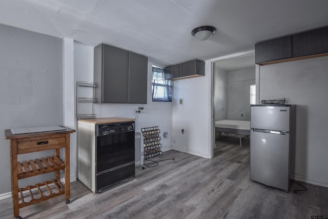 kitchen featuring light wood-style floors, wood counters, baseboards, and freestanding refrigerator