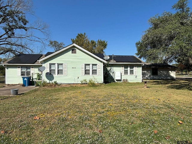 rear view of house featuring solar panels and a yard