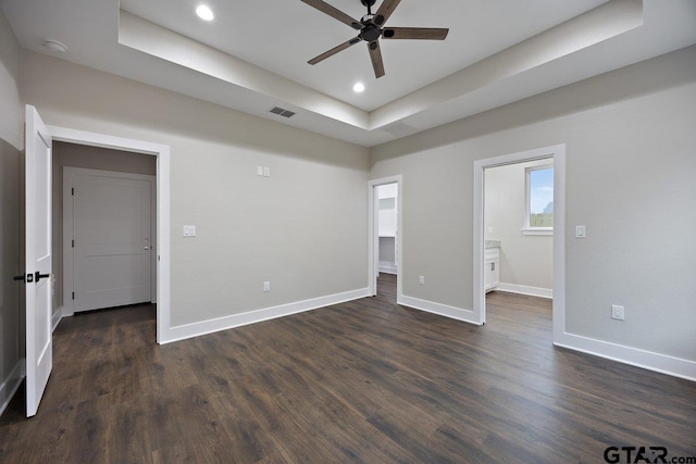 unfurnished bedroom with ceiling fan, dark hardwood / wood-style floors, and a raised ceiling