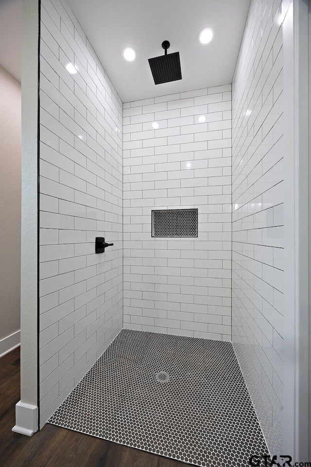 bathroom with tiled shower and hardwood / wood-style floors