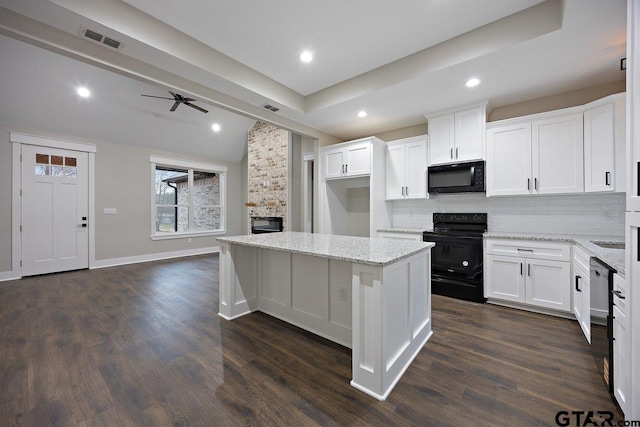 kitchen with light stone countertops, black appliances, white cabinets, and a kitchen island