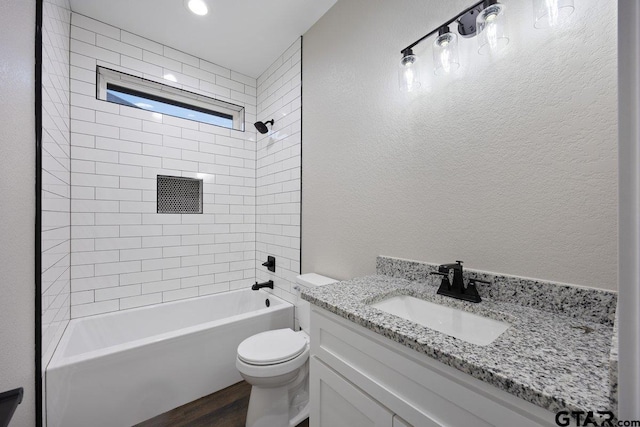 full bathroom featuring vanity, wood-type flooring, tiled shower / bath, and toilet