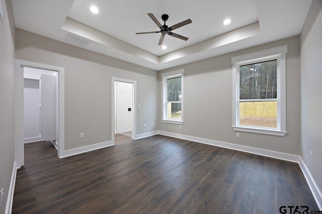 unfurnished room featuring a raised ceiling, dark wood-type flooring, and ceiling fan