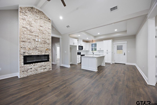 kitchen with lofted ceiling, a large fireplace, white cabinets, a kitchen island, and dark hardwood / wood-style flooring