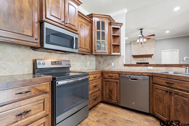 kitchen with tasteful backsplash, crown molding, sink, and appliances with stainless steel finishes