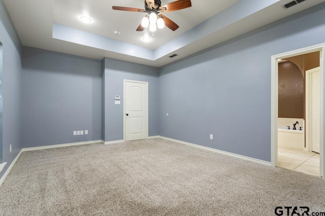 empty room featuring light colored carpet, a raised ceiling, and ceiling fan