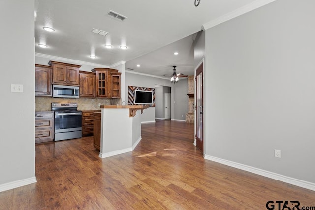 kitchen featuring ornamental molding, tasteful backsplash, stainless steel range with electric stovetop, and a breakfast bar area