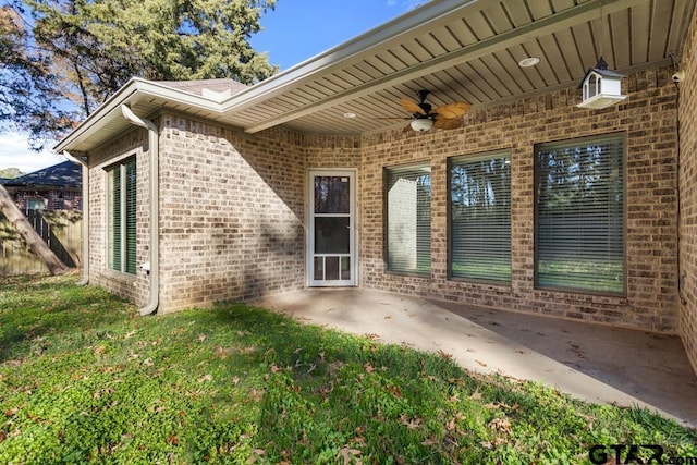 view of exterior entry with a yard, ceiling fan, and a patio area